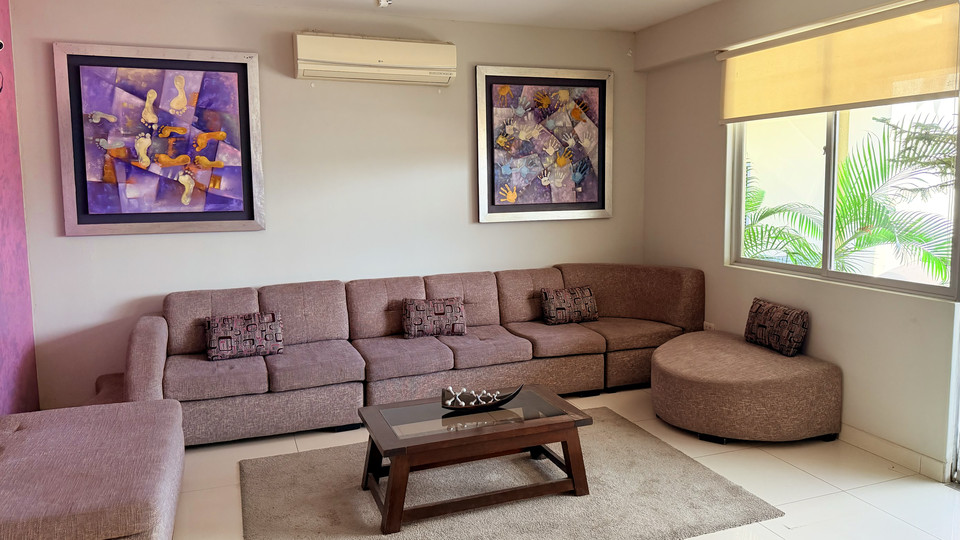 Sala de espera del ingreso principal, con sofá en L y ventanales al jardín