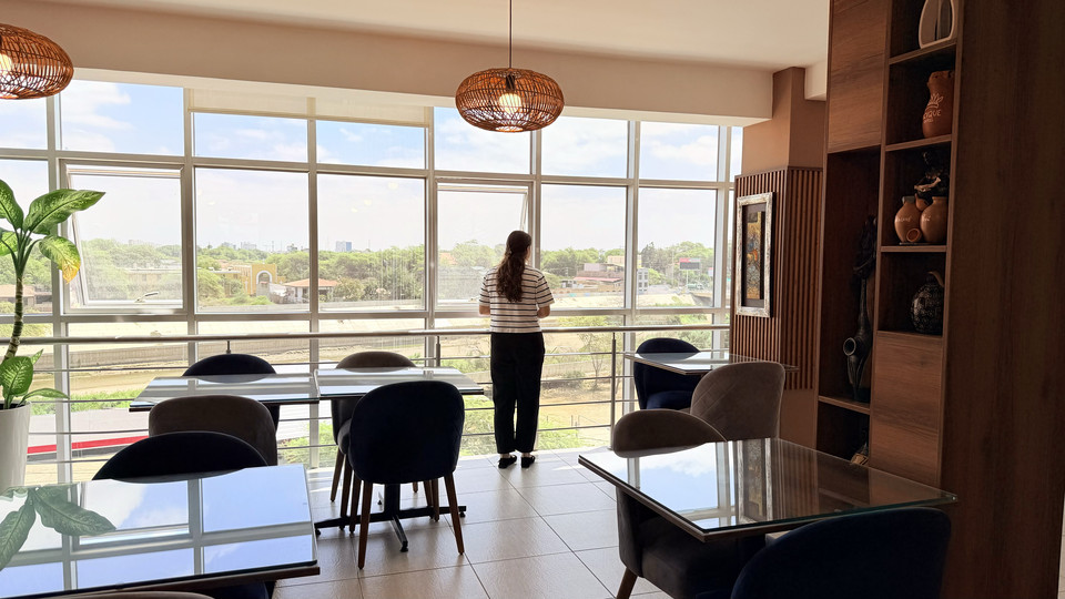 Cafetería del Cacique Hotel con ventanales de piso a techo y vista a la ciudad de Piura