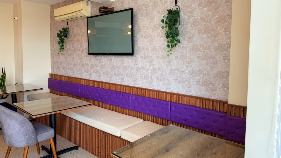 Zona de desayunos del Cacique Hotel, con banca tapizada y televisor